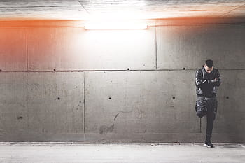 Joven, Hombre, De pie, Delantero, Concreto, Pared, arquitectura, oscuro, luces, millennials, personas