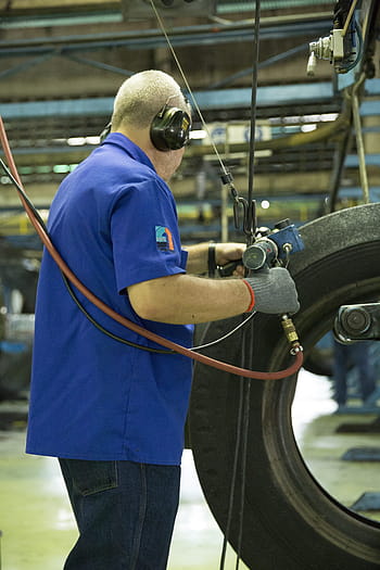 man, holding, gray, blue, air power tool, tire, work, manufactures, construction worker, manufacturing, industry