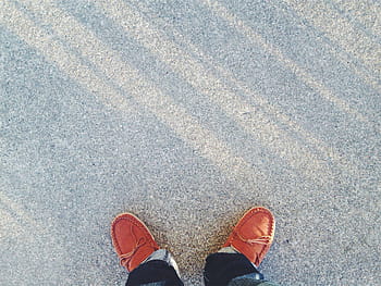 person, wearing, orange, boat shoes, tassel, brown, moccasins, standing, shoes, jeans, denim
