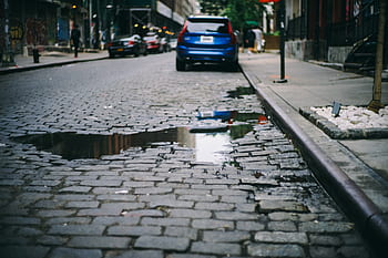 road, street, car, vehicle, parking, sidewalk, pole, water, people, man, walking