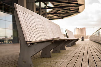 wood bench, outdoor seating, wooden slats, metal frame, public space, modern design, urban furniture, cityscape background, wooden deck, architectural structure, cloudy sky