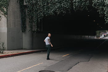 man, shirt, stands, road tunnel, green, vines, daytime, people, walking, alone, road