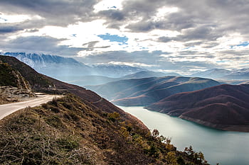 sky, clouds, sunlight, mountains, peaks, cliffs, valleys, hills, trees, road, nature