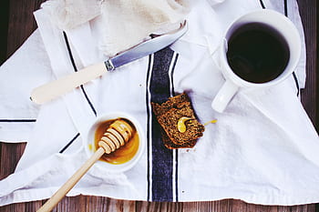 loaf, bread, knife, tea, cup, table, napkin, cloth, syrup, butter, honey