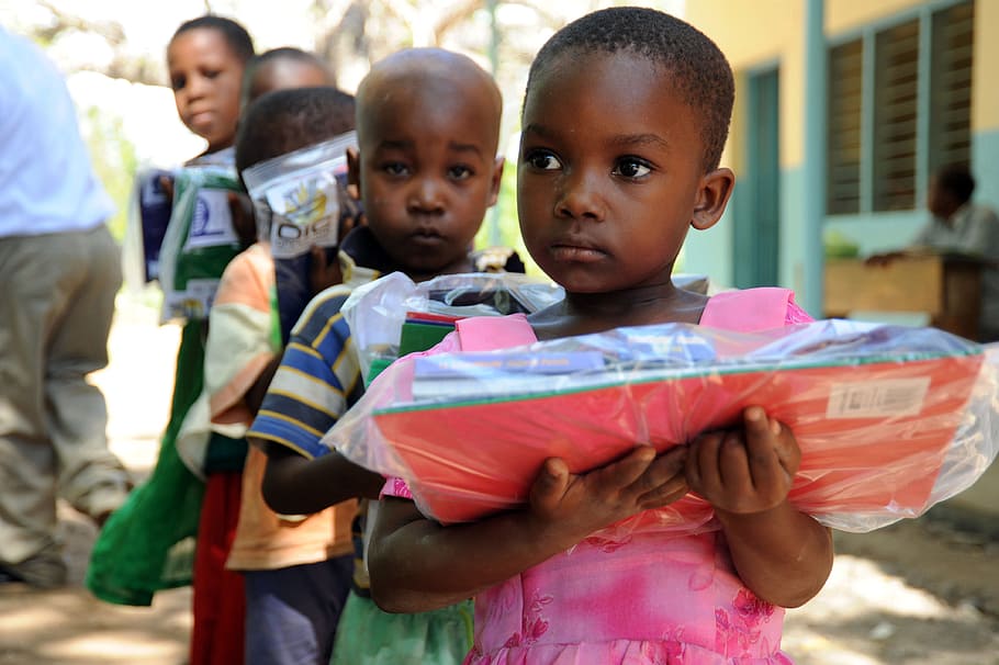 children, holding, school supply packs, tanga, tanzania, care packets, boys, outside